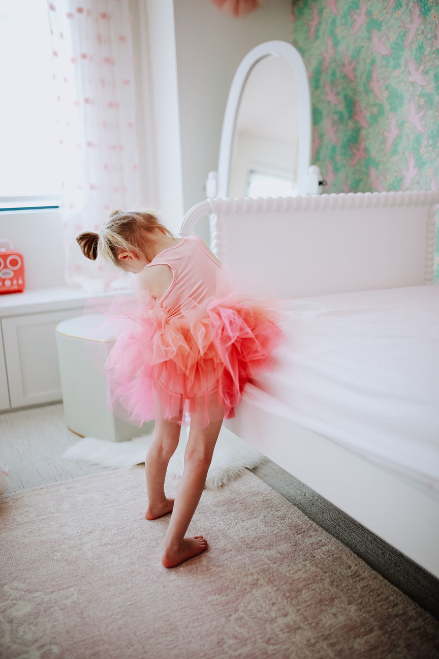 Little girl making her bed in pink tutu