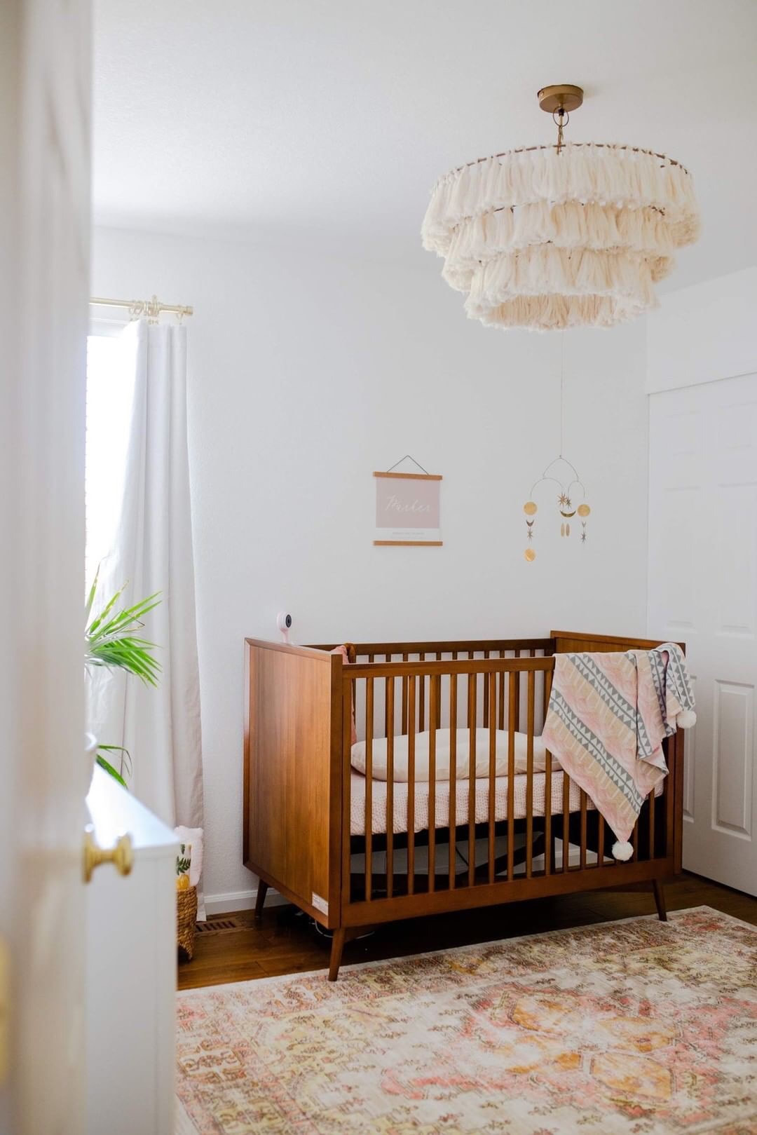 baby nursery with dark woo, mid-century modern crib and distressed, pink and brown area rug