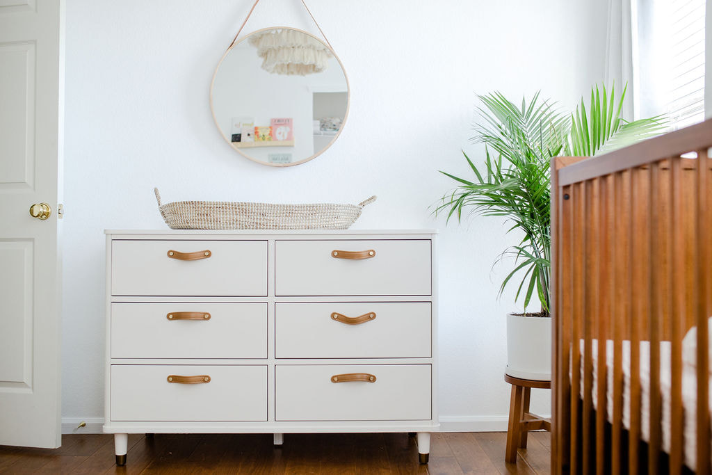 White dresser with brown leatehr pulls and round mirror, YouthfulNest Nursery Design