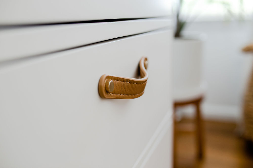 Close up of camel brown leather draw pull on white dresser,YouthfulNest Nursery Design