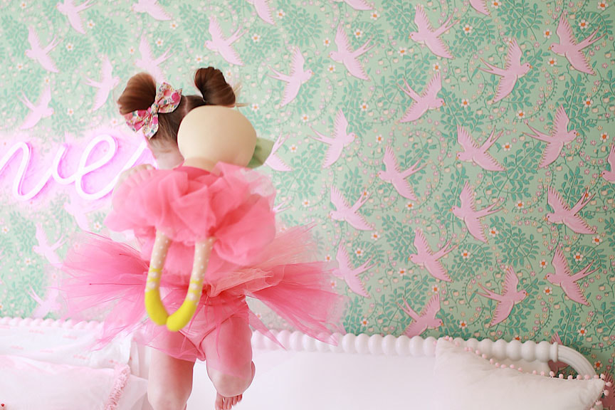 Girl jumping on bed. Pink and green girls bedrooom design