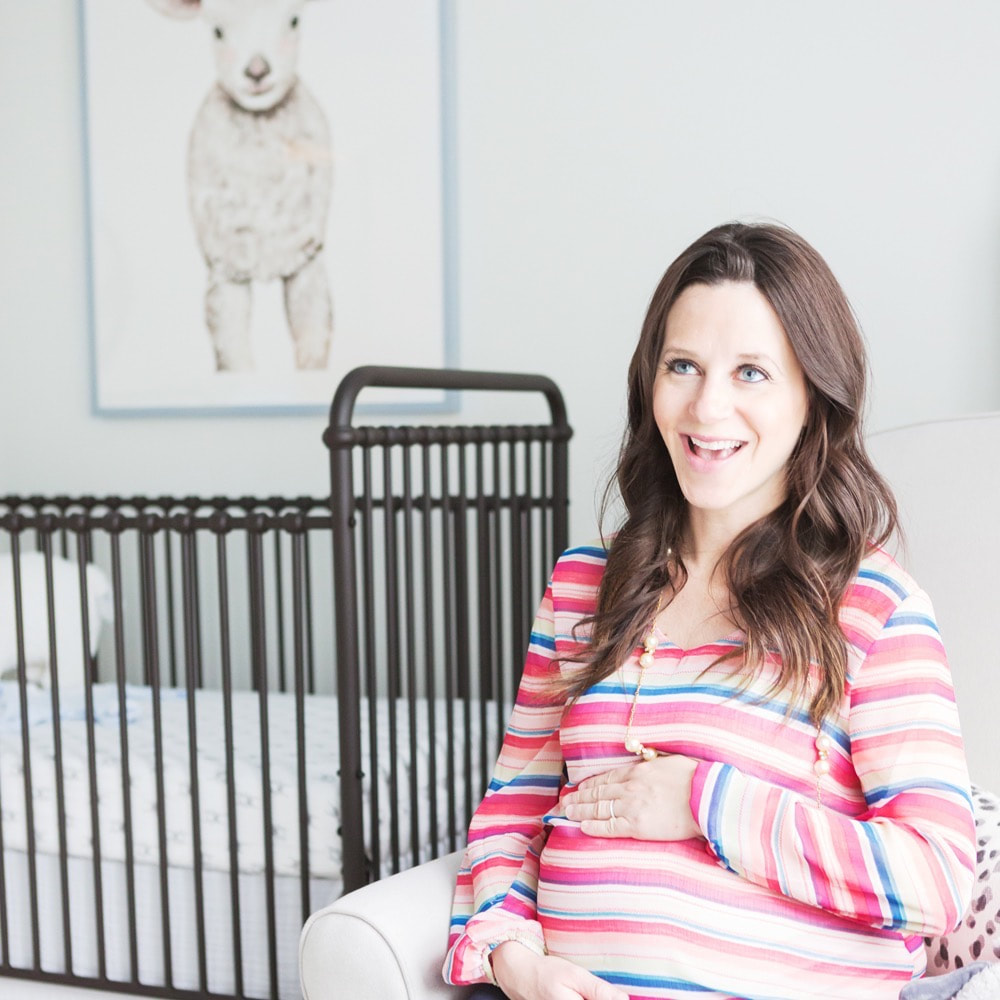 Pregnant mom smiling in her nursery